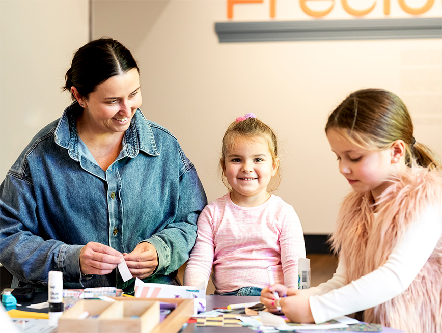 Mother and daughter smiling while enjoying a drop-in activity at the museum