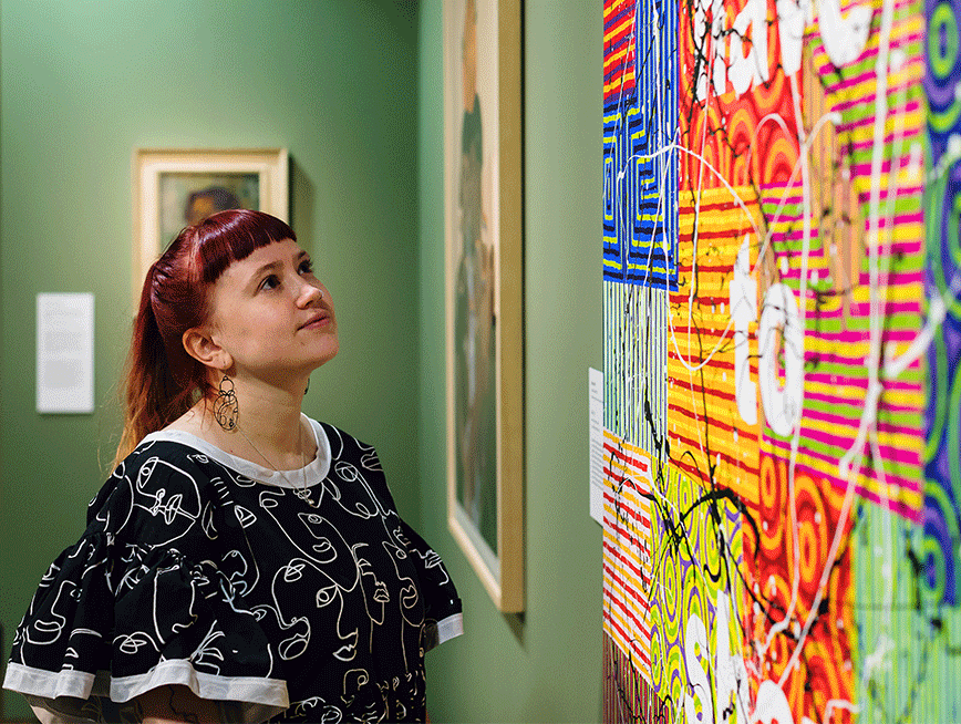 A girl looking at a painting in a gallery painted green.
