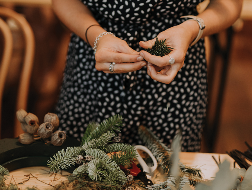A wooden table is covered in an assortment of dried botanicals and a pair of scissors with white handles.