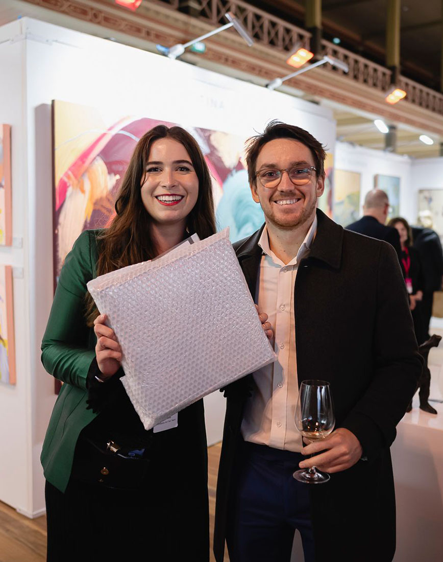 Happy couple smiling with new purchased piece of art at the fair