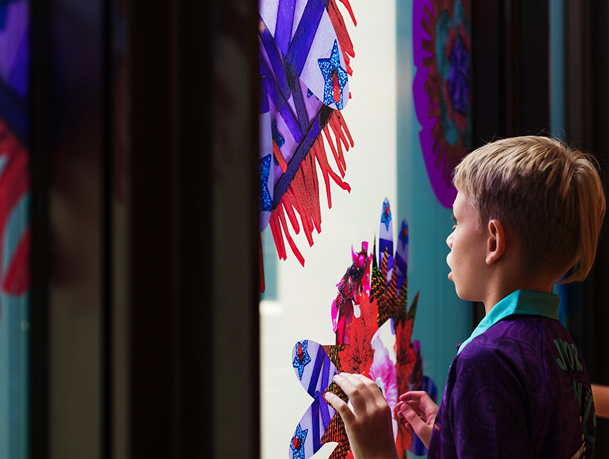 A child looking out of a glass panel decorated with vinyl decal.