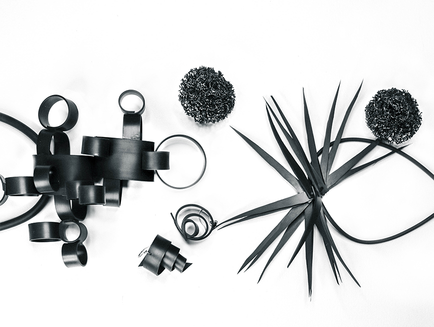 Black and white flat lay image of MIKAs rubber jewellery, shaped as spikes, coral like spheres, cylinders and spirals.
