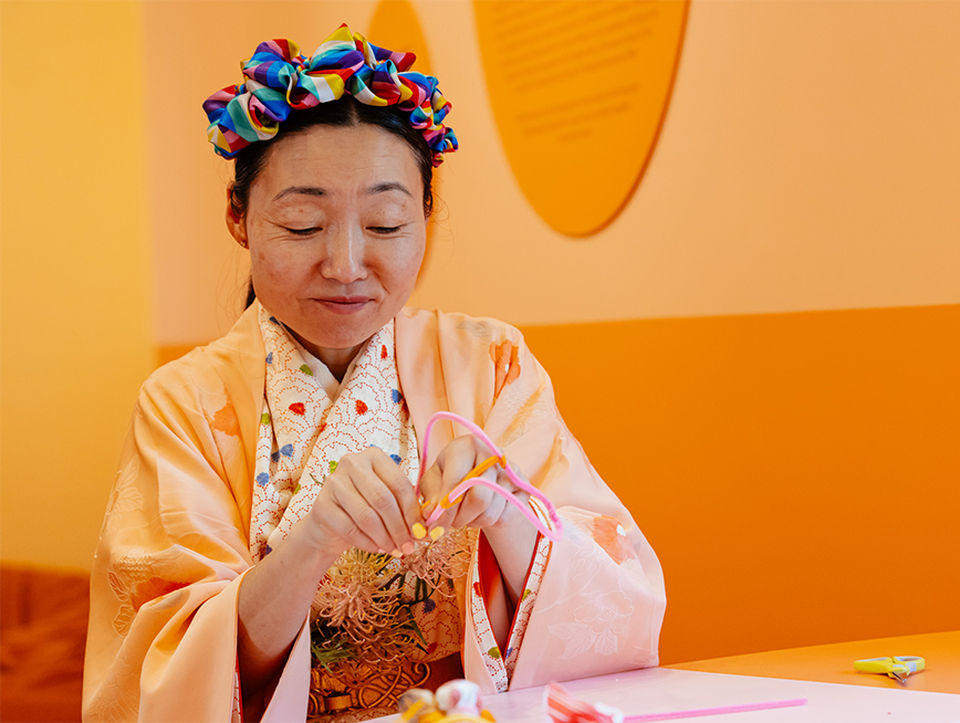 Hiromi Tango wearing a kimono and headband crafting with her hands