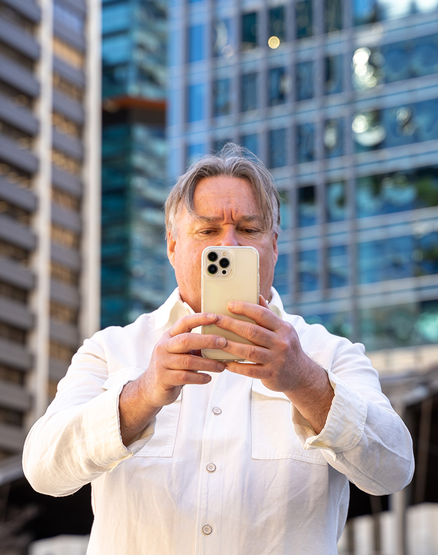 Carl Warner in the city holding an iPhone directly in front of his face.