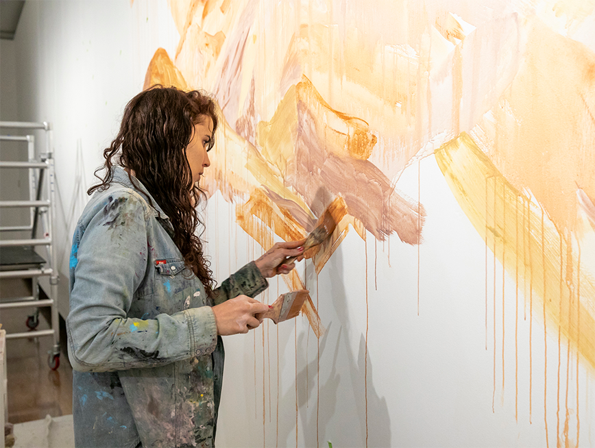 Artist in Residence Jody Rallah painting on a wall