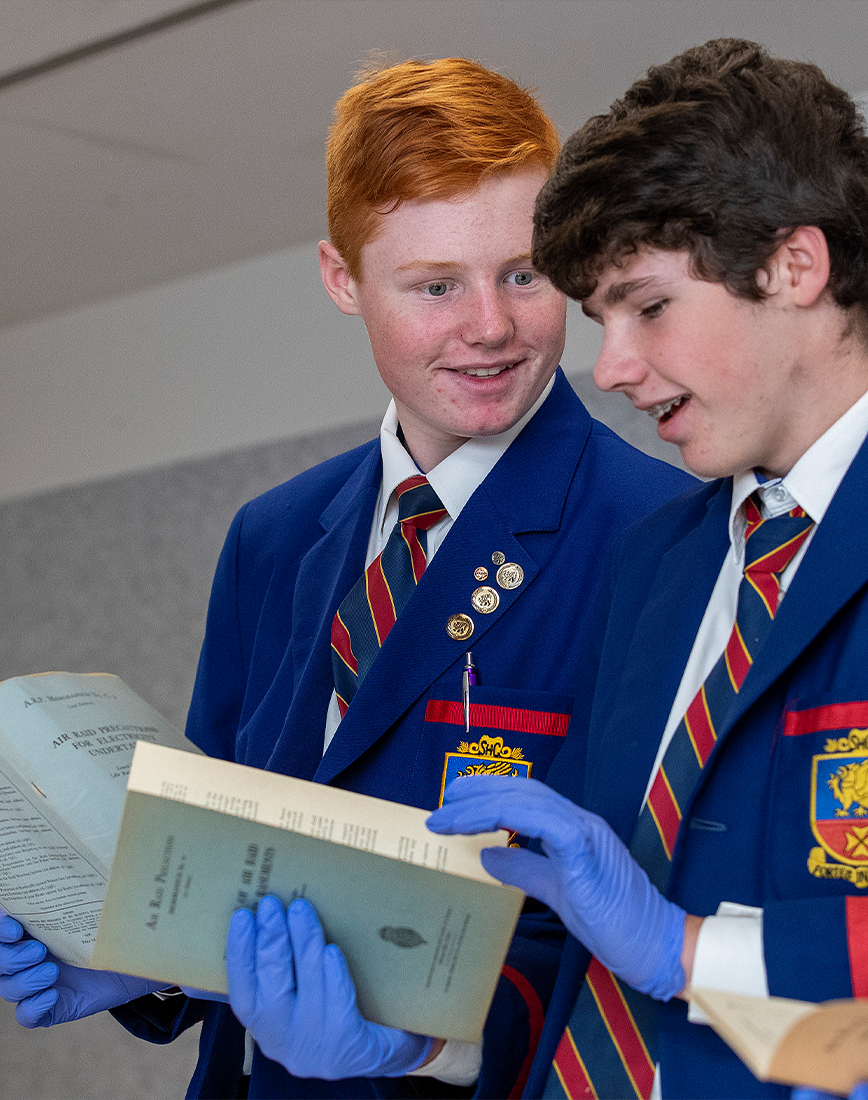 Two students examining old blue booklets