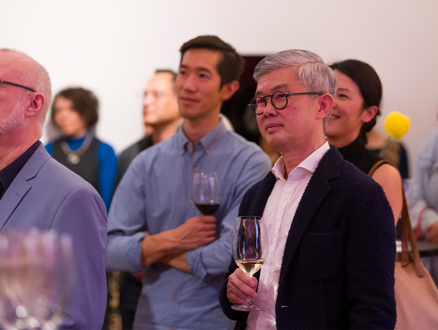 A group of visitors standing with a glass of beverage.