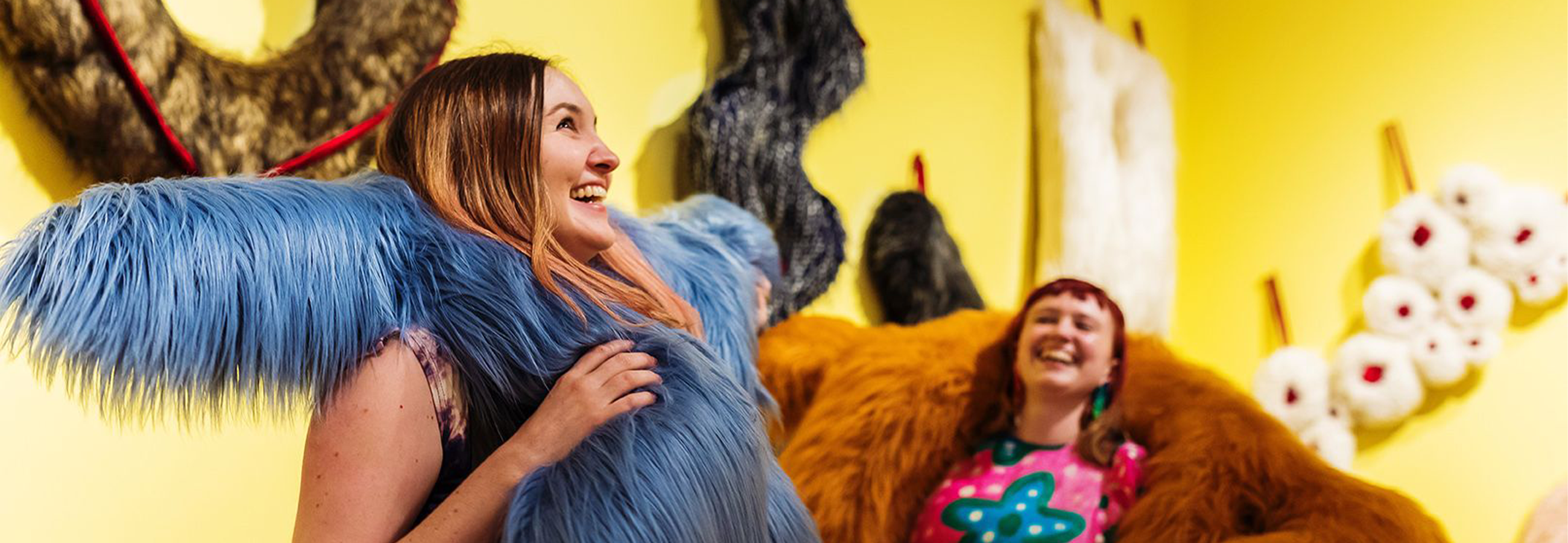 Two women inside Play Moves exhibition. One is wearing blue furry costume and another wearing brown costume.