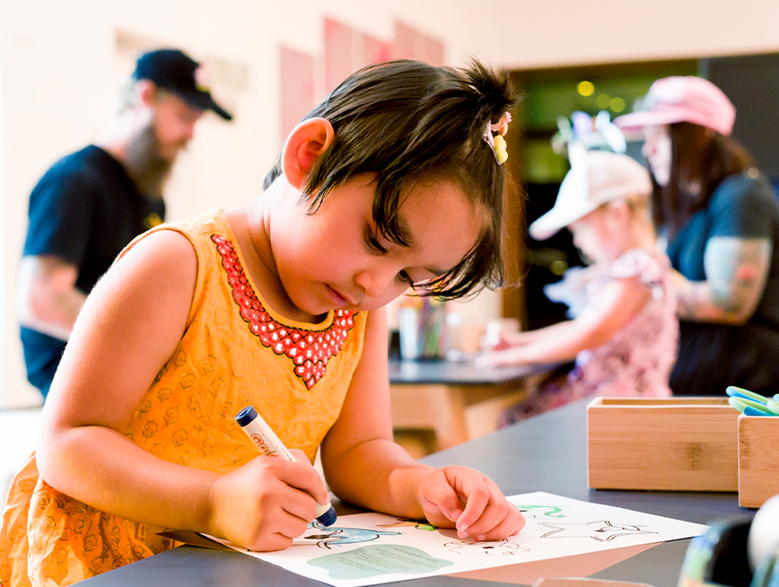 A girl in a orange dress drawing.