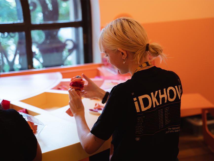 A young woman holding a fabric flower in the gallery.