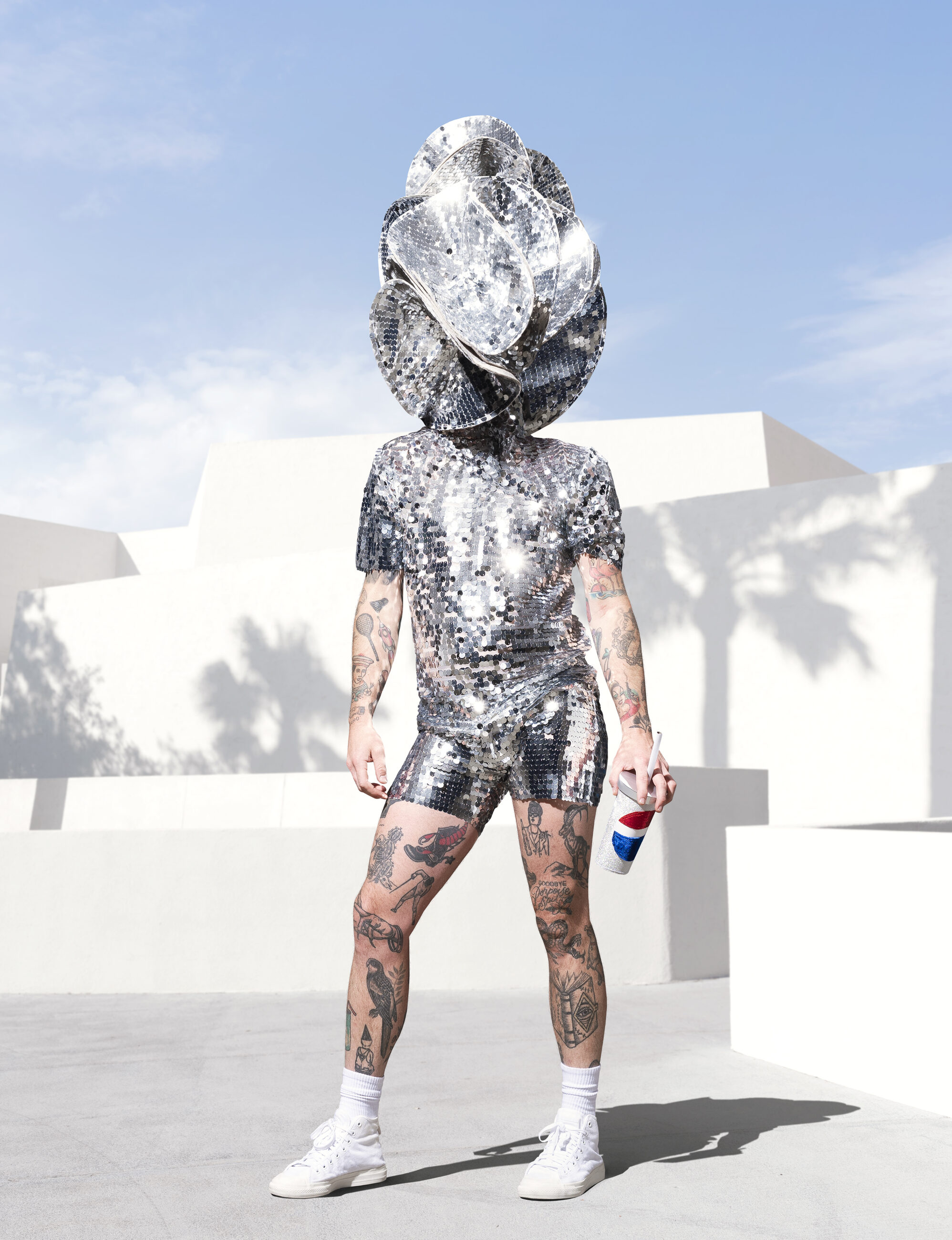 Silver mirror costume worn by a person, posing with a white building and blue sky behind them.