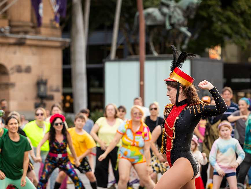 100 and more participants at King George Square Showdown. The participants are following the dance moves of the lead dancer.