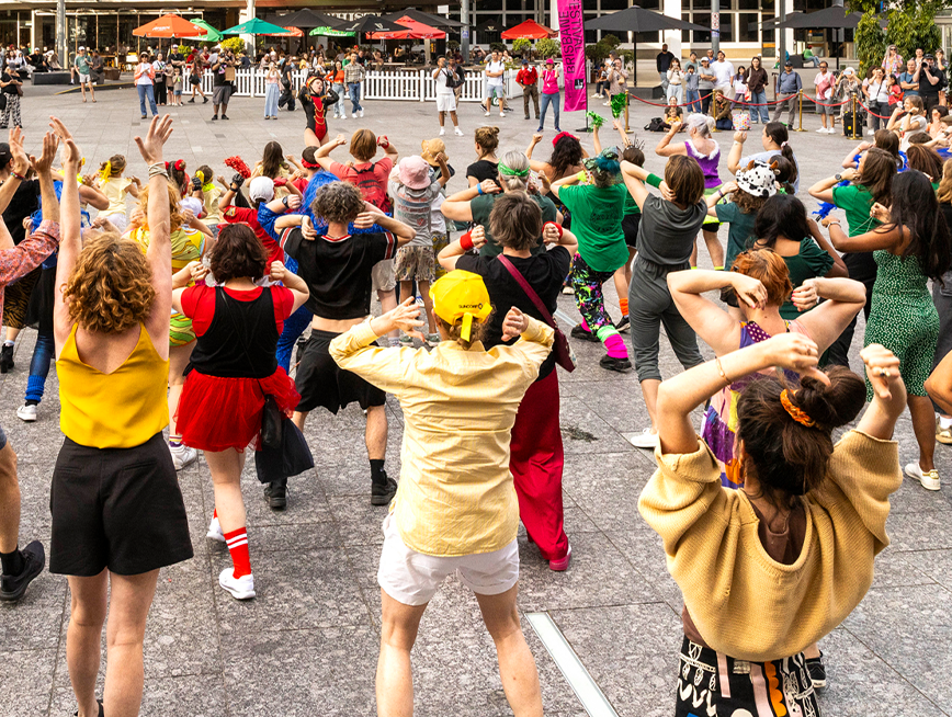 100 and more participants at King George Square Showdown. The participants are following the dance moves of the lead dancer.