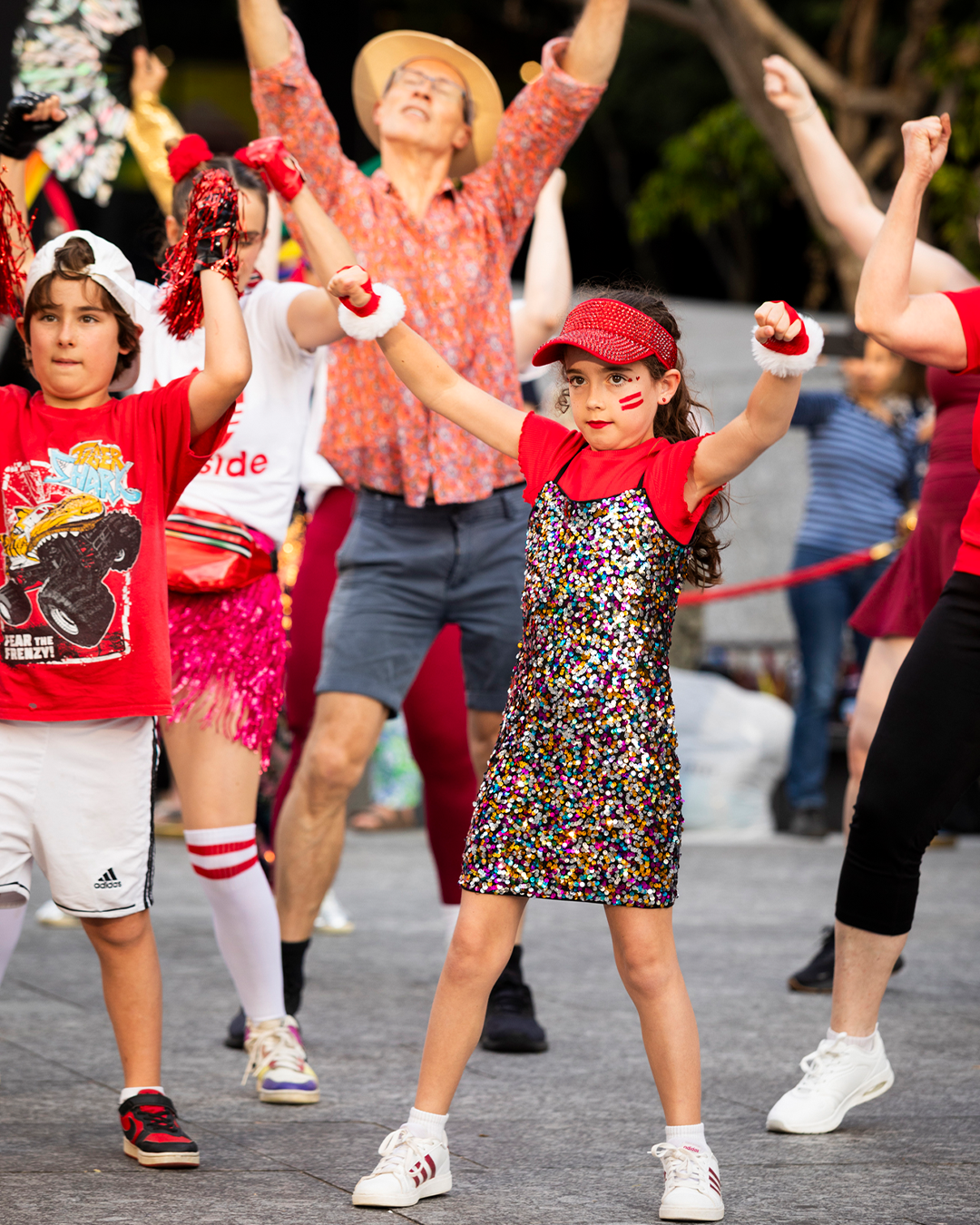Kids in red clothes dancing with their hands up.