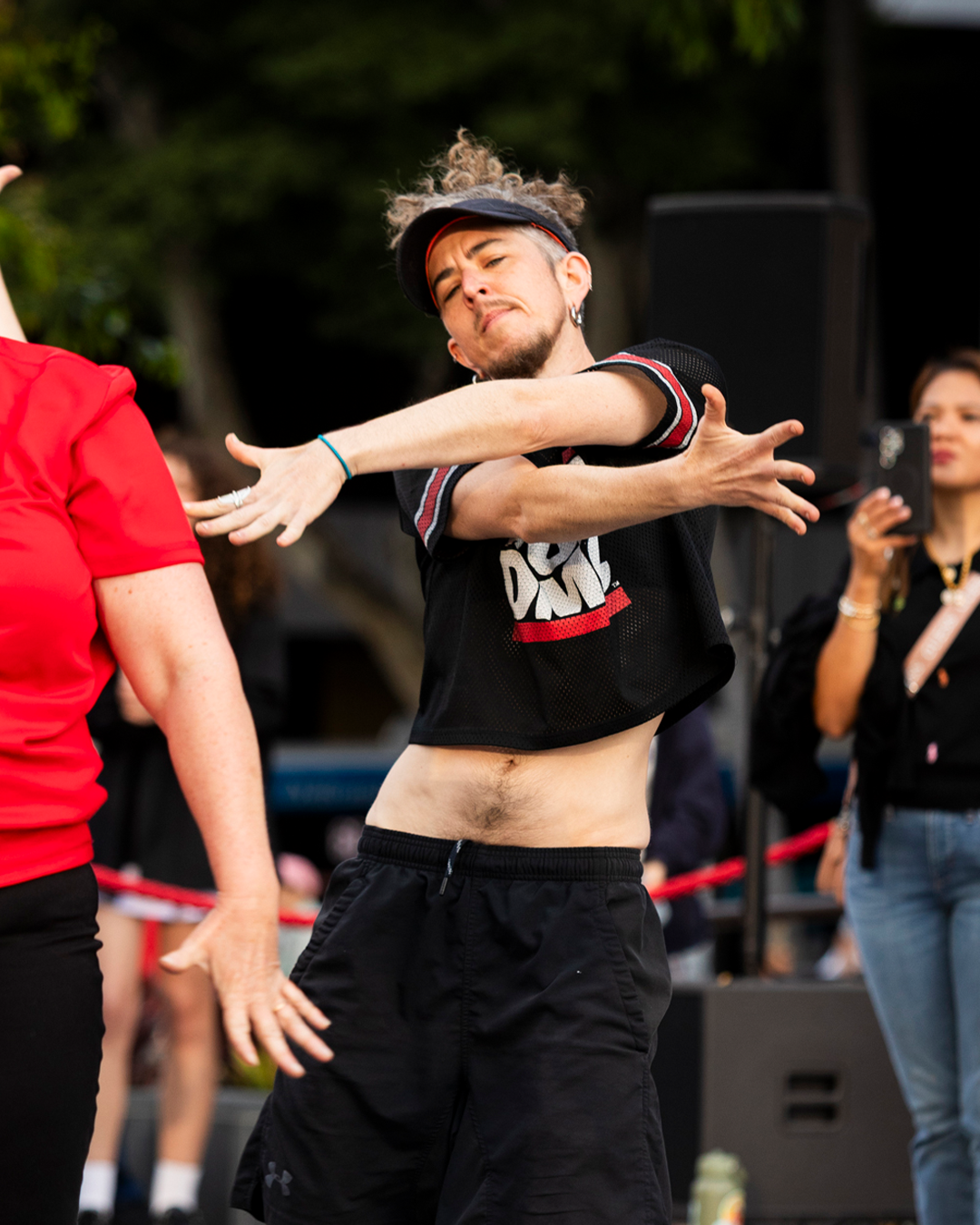 A dancer in red dancing with his hands crossed.