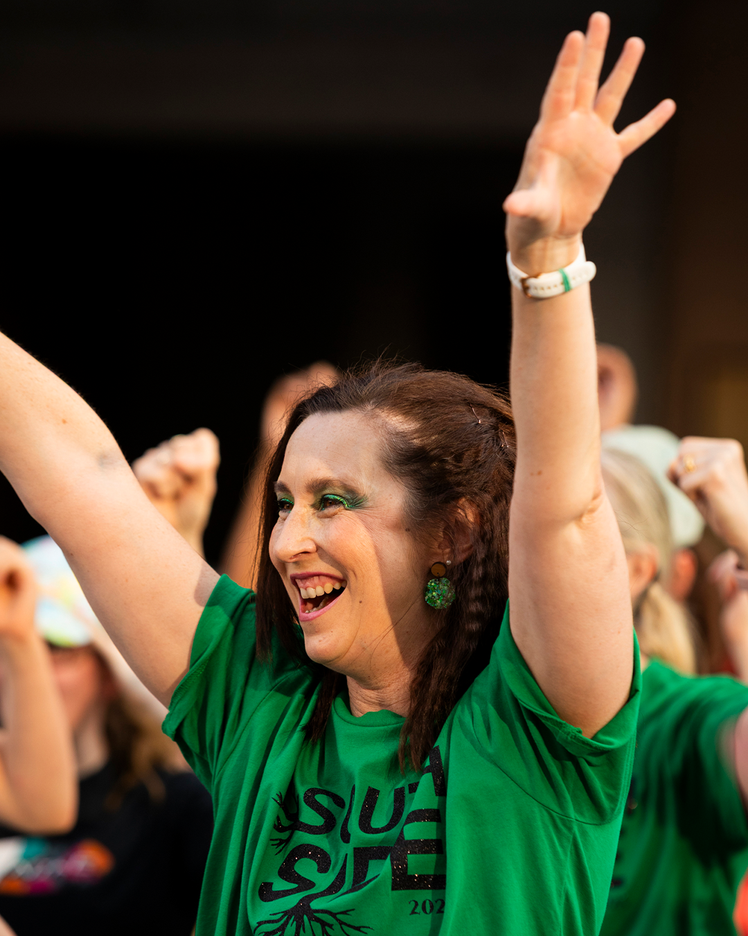 A woman in green with hands up.