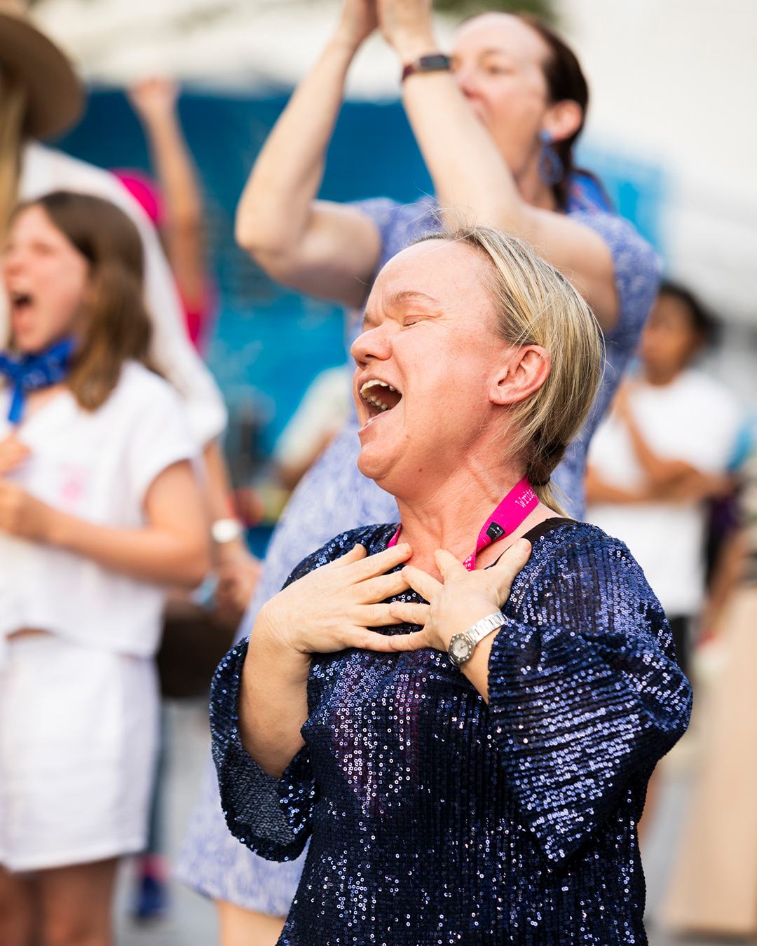 A woman holding their hands to their chest. She's laughing with her eyes closed.