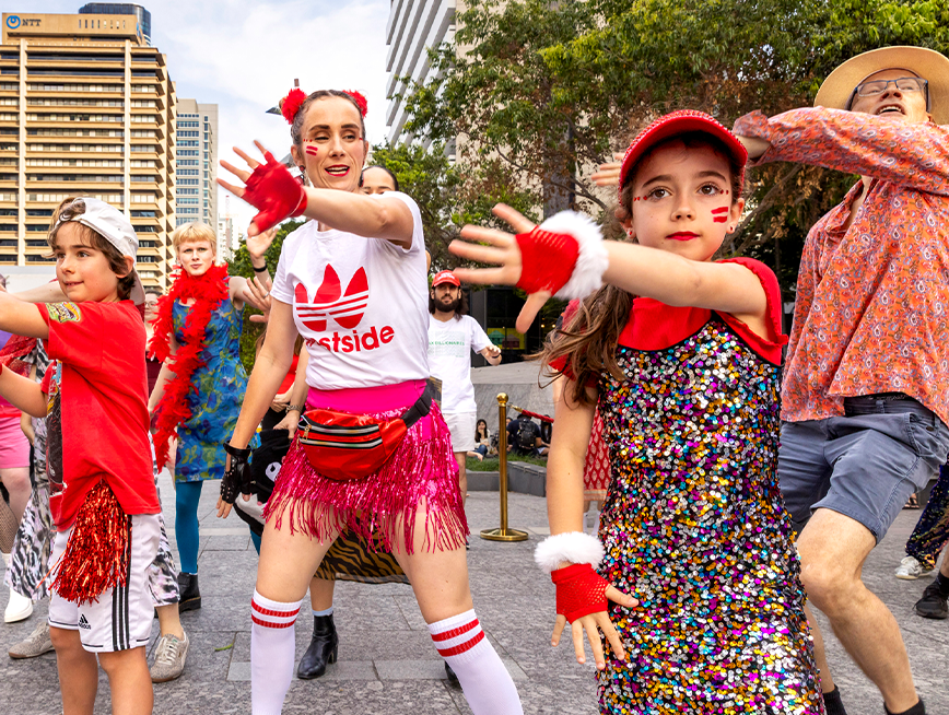 A group of people wearing red clothes, dancing.