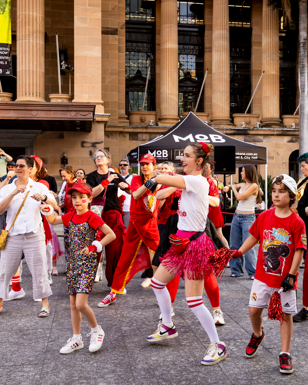 A group of people wearing red clothes, dancing.