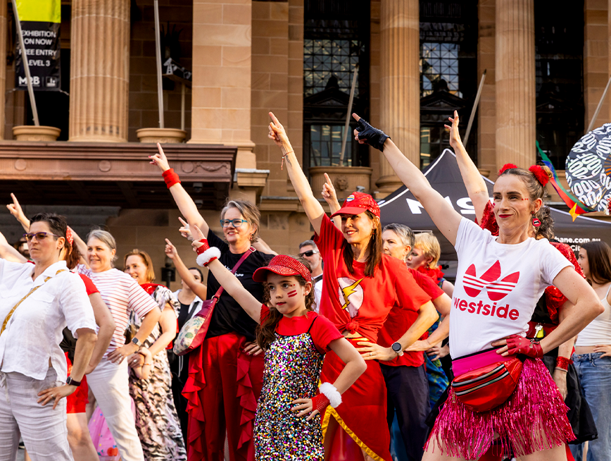 A group of people wearing red clothes, dancing.