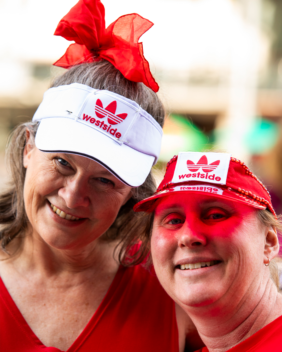 Two women wearing red accessories smiling at the camera.