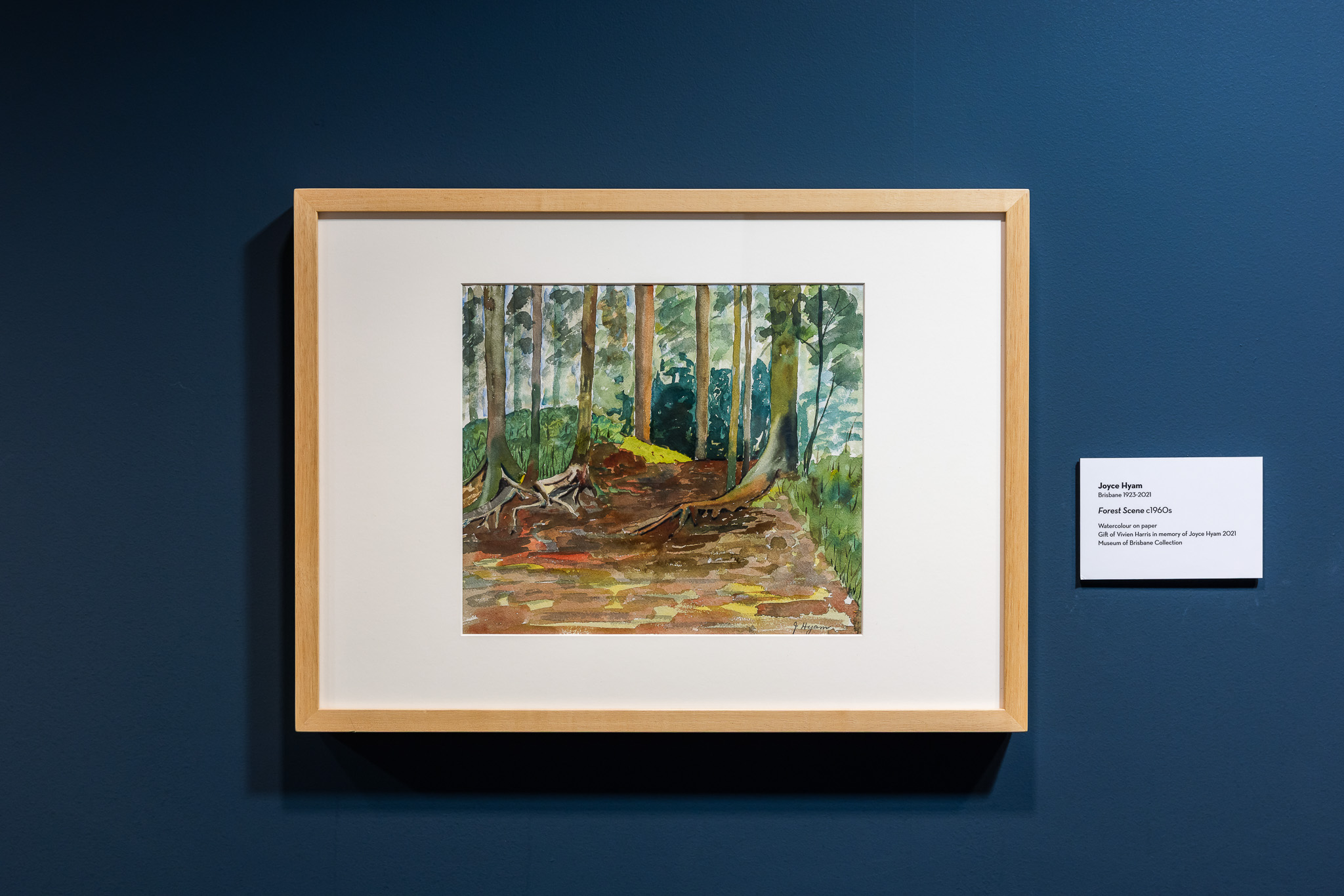 Watercolour painting of forest with green trees and brown earth.