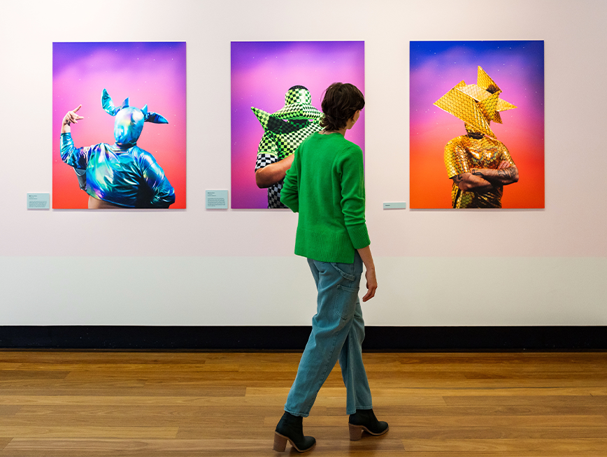 A woman walking around a portraits photographic exhibition.