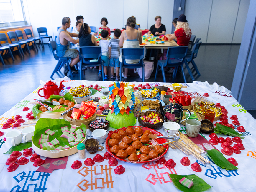 A display of ceramic food. In the background, a group of people sitting around the table.