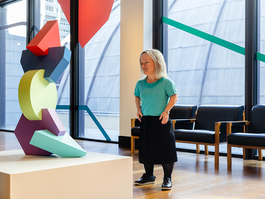 A woman looking at a colourful geometric sculpture.