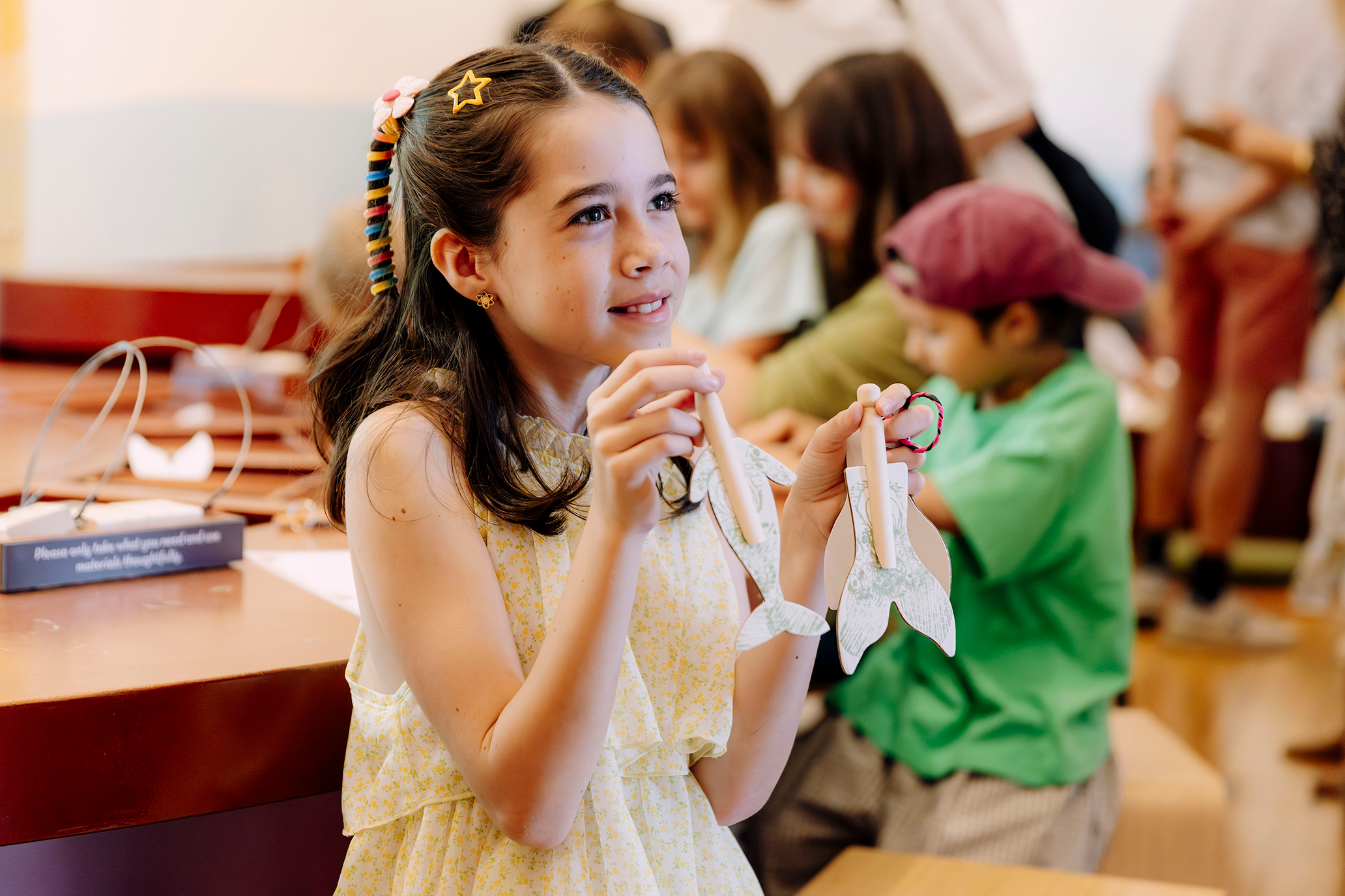 A girl holding a mermaid and dugong dolly peg.