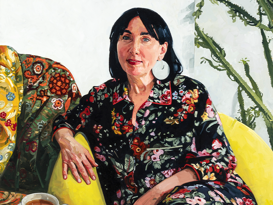 Painting of Pamela Easton seated on a bright yellow couch. A cup of tea rests beside her. She is wearing a floral top and matching pants, accessorised with large round white earrings. She gaze directly at the viewer.
