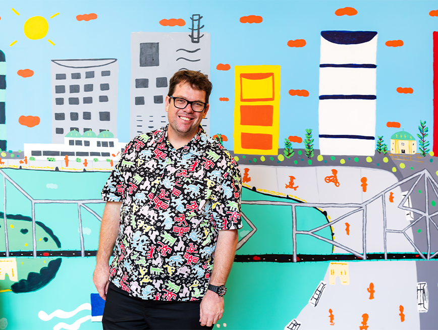 Martin standing in front of his mural, smiling at the camera.