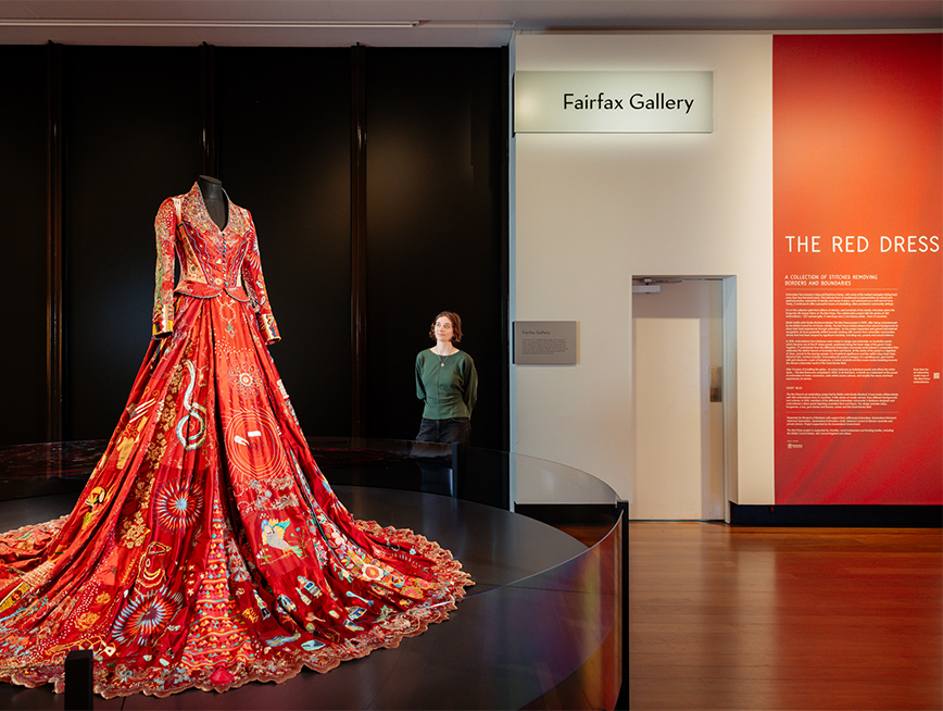 A woman looking at a delicately embroidered red dress.