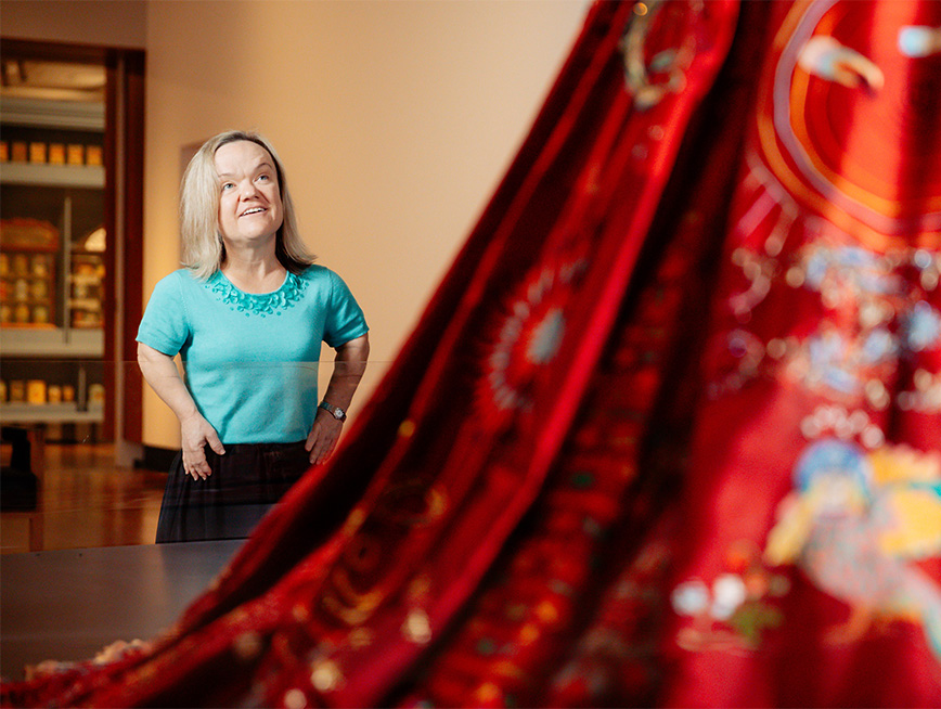 A woman looking at a delicately embroidered red dress.