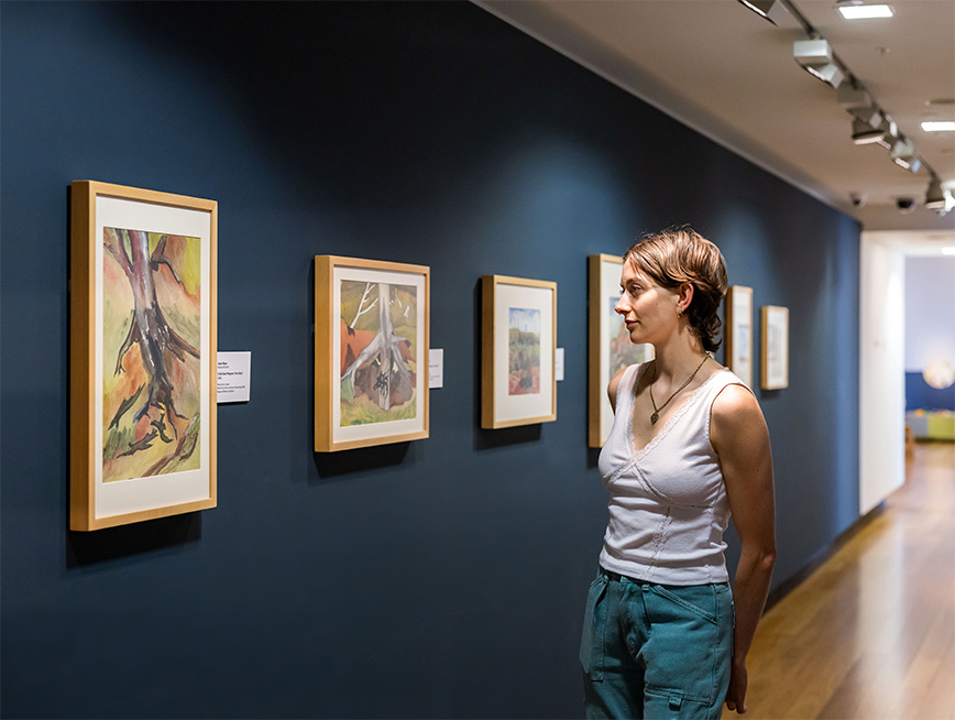 Woman looking deeply into a framed artwork on the wall