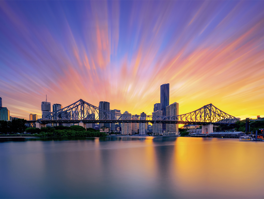 Brisbane cityscape. There are buildings and story bridge over Brisbane river in sunset.