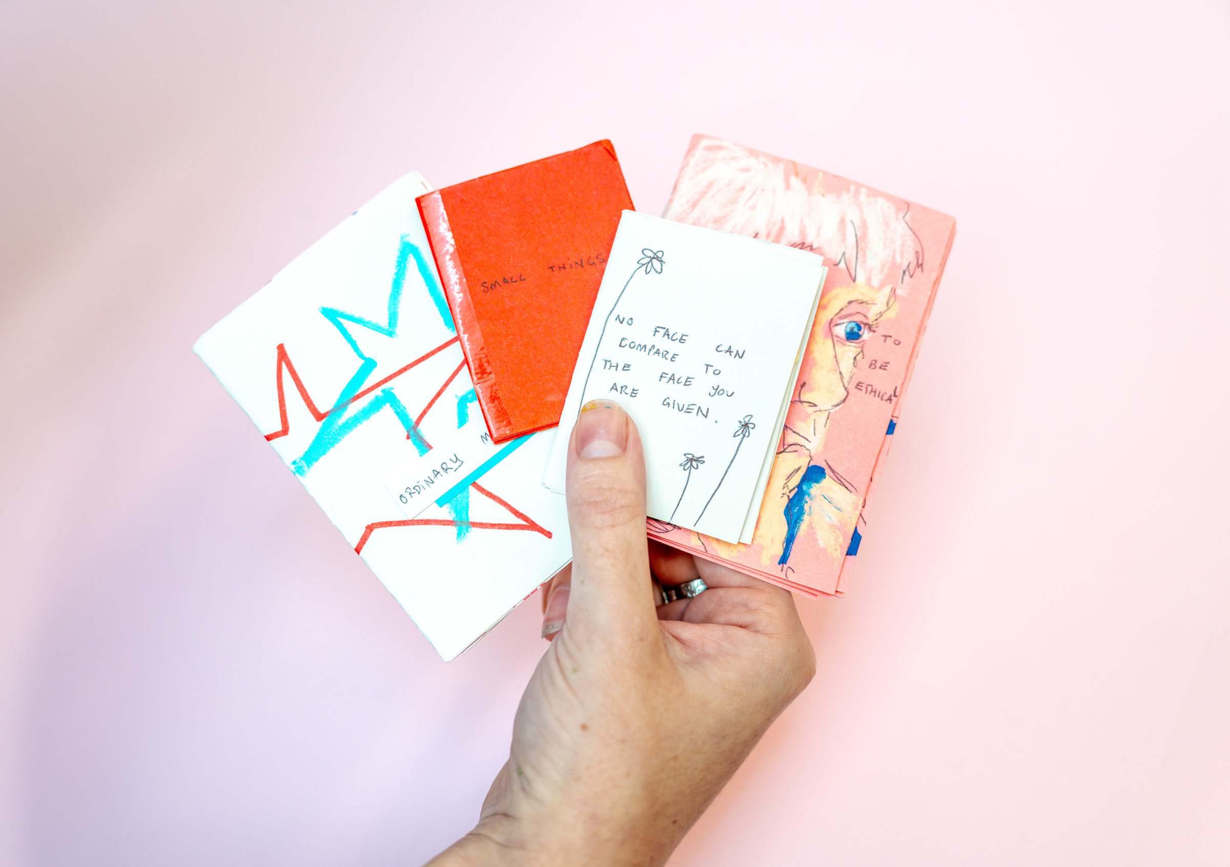 Hand holding four small zines