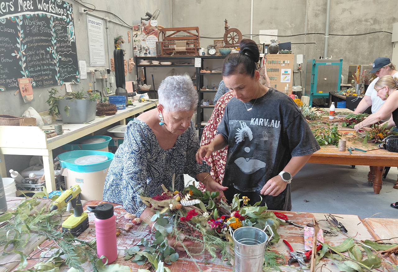 two people looking at a bunch of flowers and thinking about how to assemble them