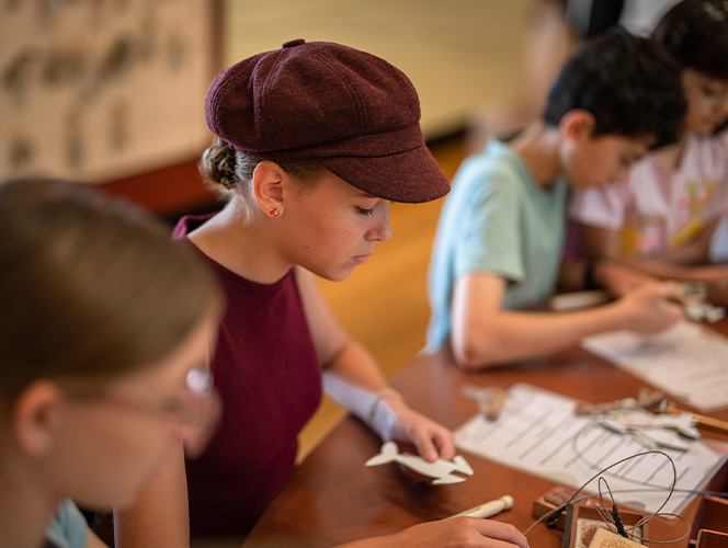 A group of kids making craft mermaid dolly pegs.