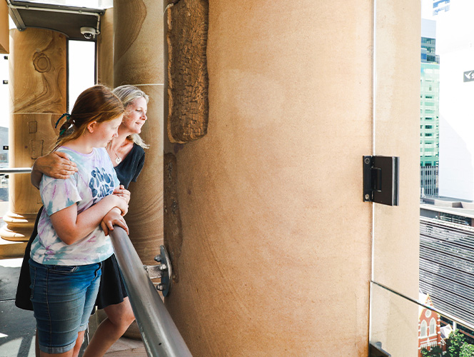 A mum and daughter looking out of the clock tower.