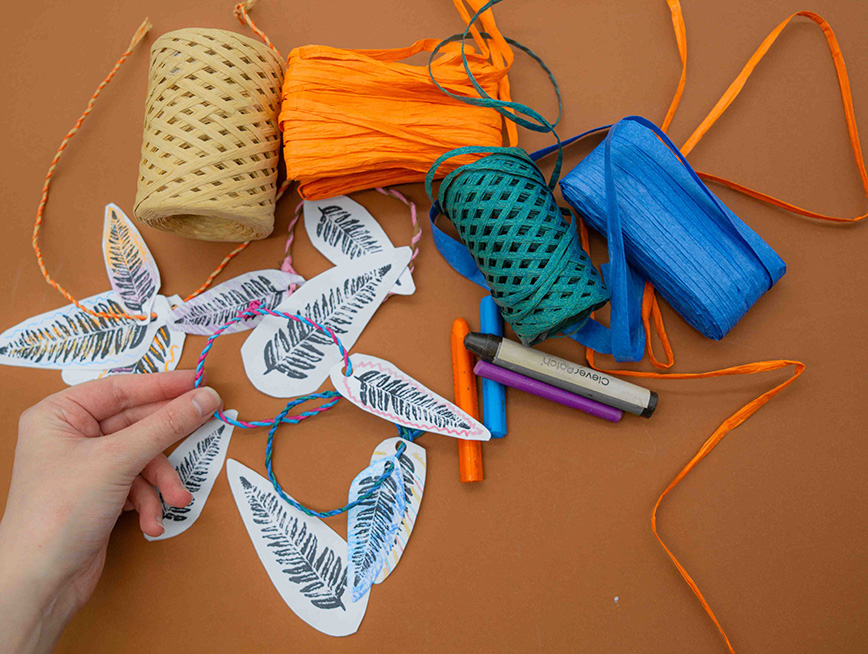 Paper cut-out ferns surrounded by thread and raffia.
