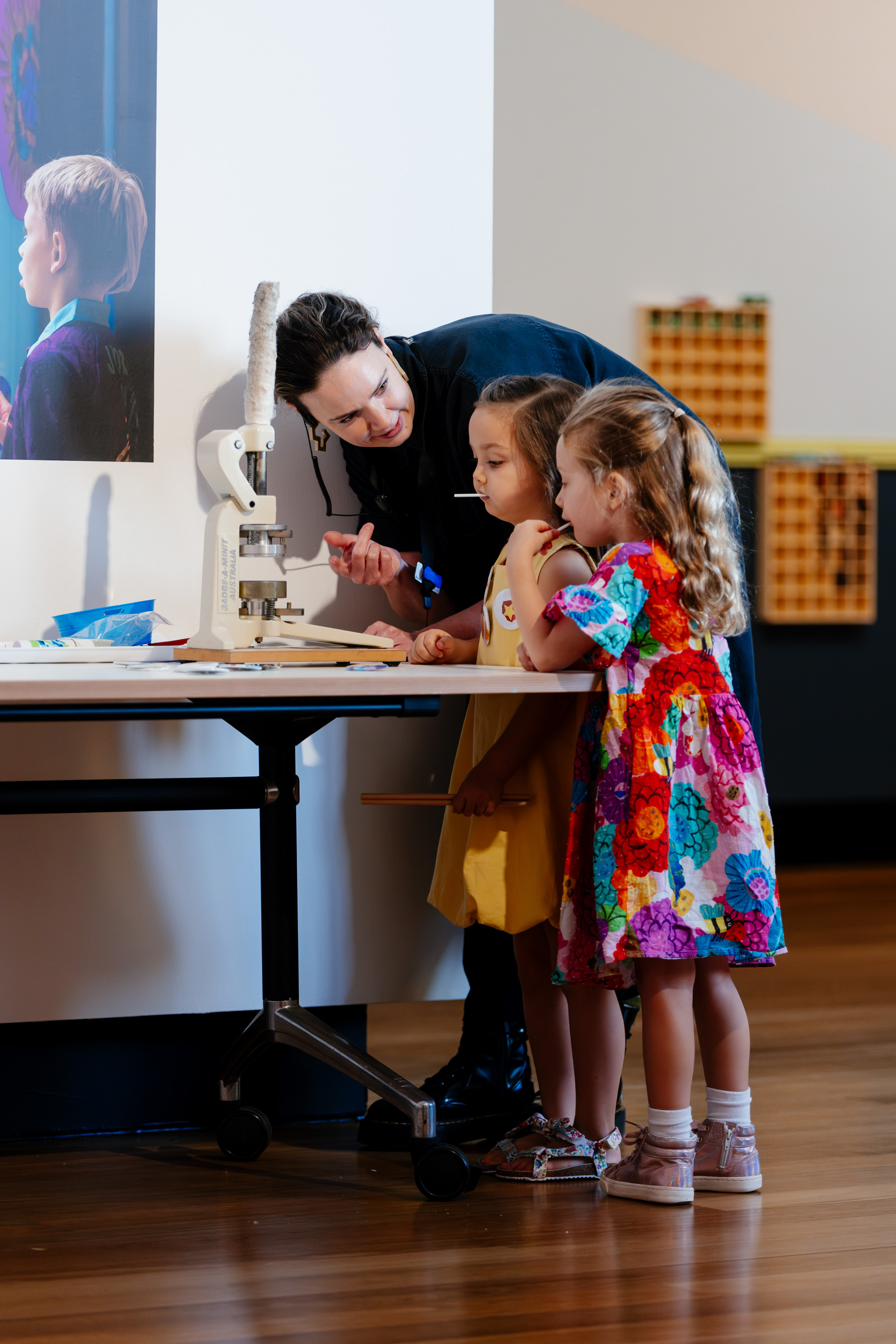 Museum staff helping children make a badge with the badge machine