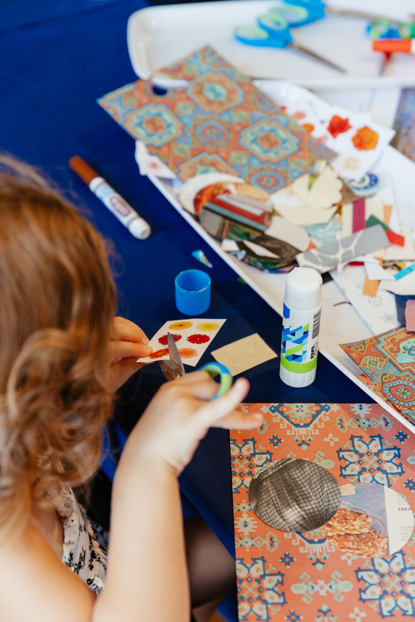 Small child making badges with cut up pieces of paper and glue.
