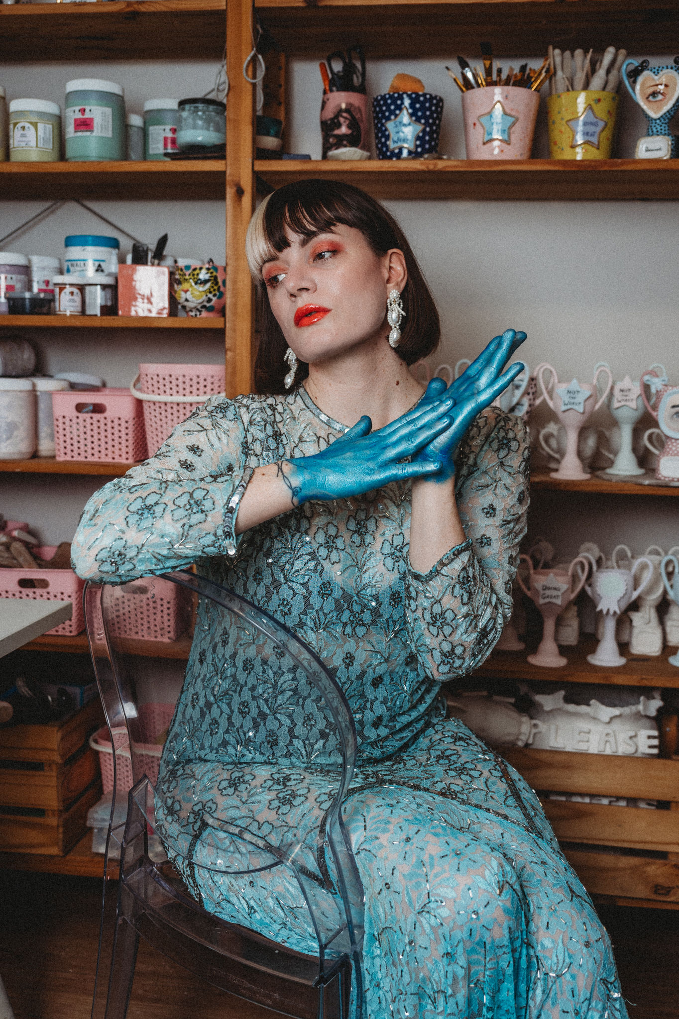 Woman looking elegant with her ceramics on display in a shelf behind her