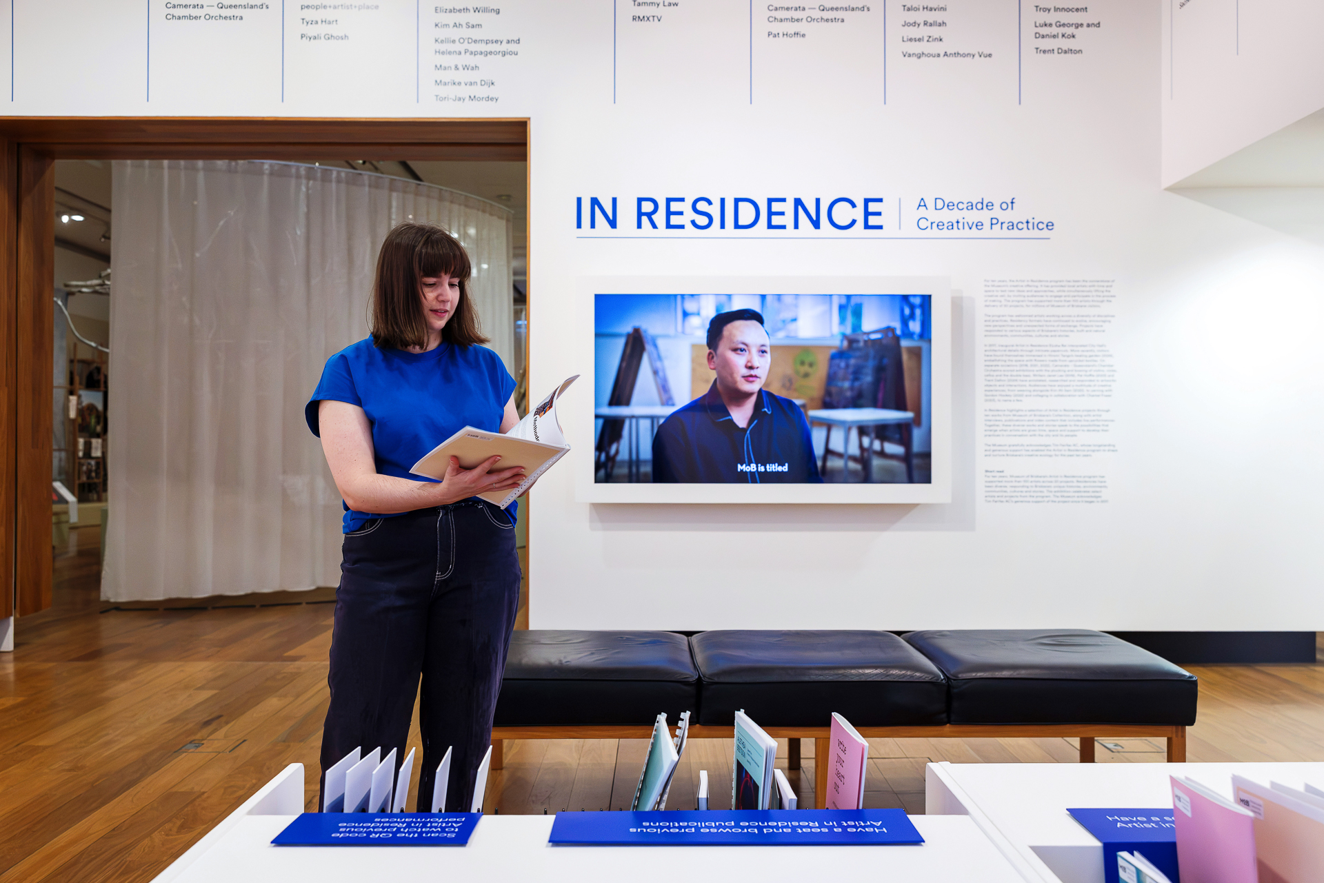 A visitor looking at in exhibition materials at Museum of Brisbane's In Residence exhibition.