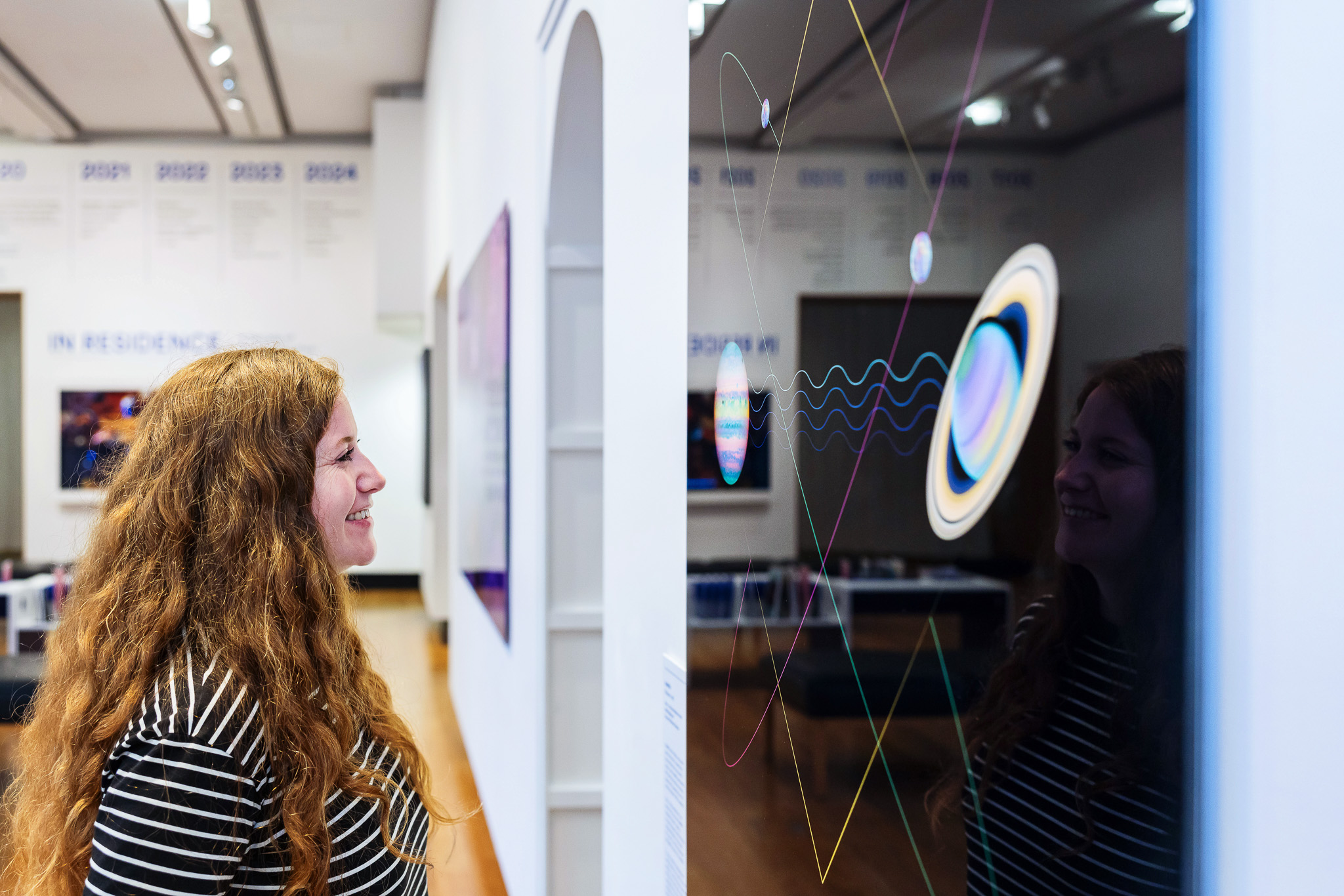 Visitors at In Residence exhibition, looking at a work by Man&Wah.